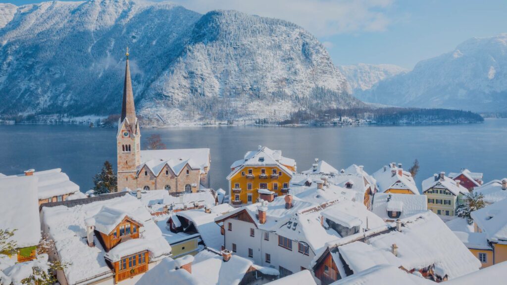 Vue d'ensemble du village de Hallstatt sous la neige, au bord du lac Hallstätter See, entouré des Alpes autrichiennes.