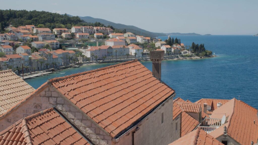 Vue sur la vieille ville de Korčula, avec ses remparts en pierre, ses toits ocre, et la mer Adriatique aux teintes bleutées en arrière-plan.
