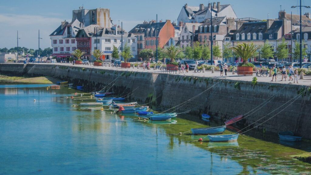 Vue sur la ville close de Concarneau entourée de ses remparts, avec les reflets dans l’eau calme du port et les premiers feuillages de printemps.