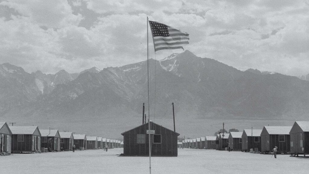 Vue d'ensemble du camp d'internement de Manzanar en Californie, où des milliers de Japonais-Américains ont été détenus durant la Seconde Guerre mondiale. Un paysage aride et montagneux entoure les baraquements, témoins silencieux d'un chapitre sombre de l'histoire américaine.